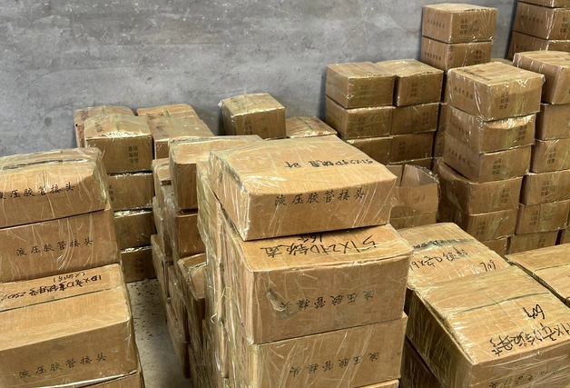 ‌A stack of packaged hydraulic fitting bundles neatly arranged on the floor, ready for shipment